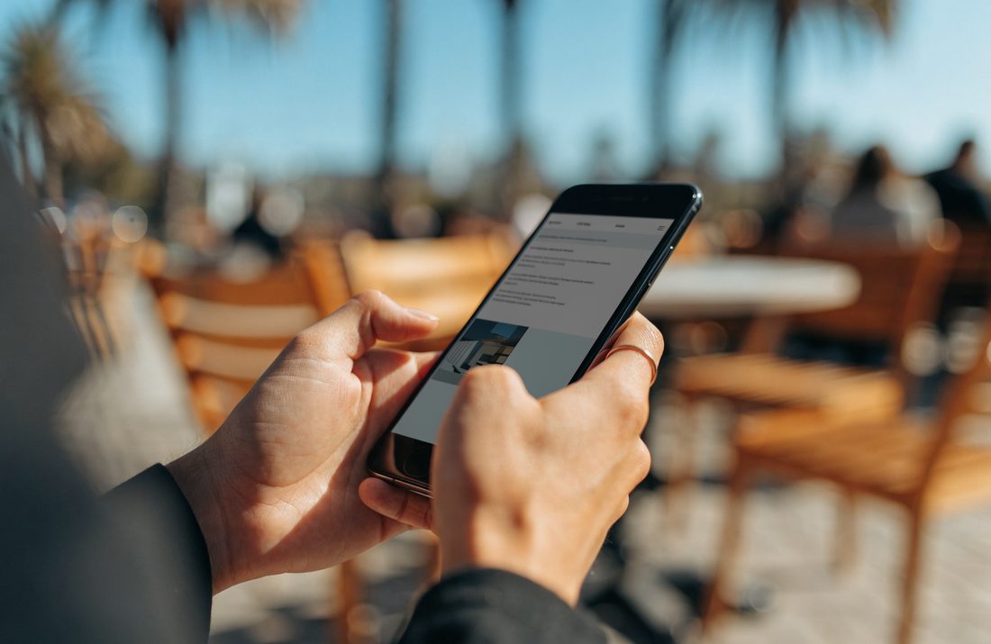 Hands holding a phone showing a clean business website outdoors