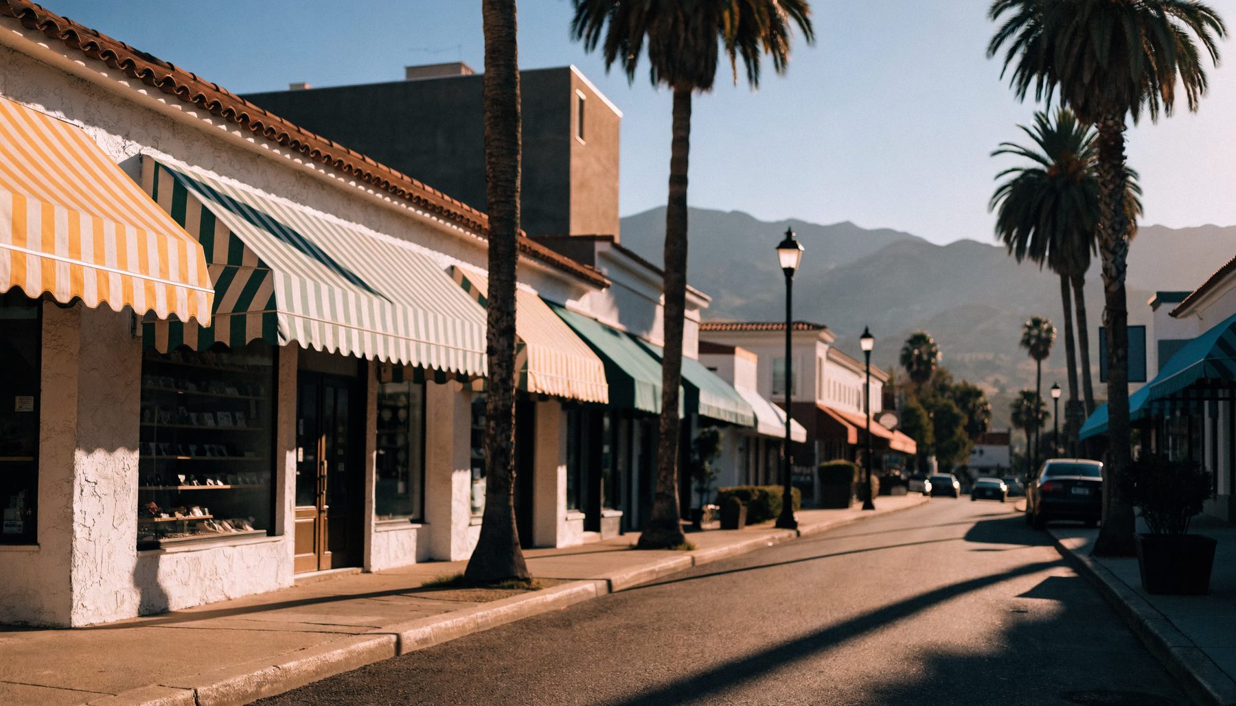 A sunny Southern California shopping street with tile roofs, awnings and palms
